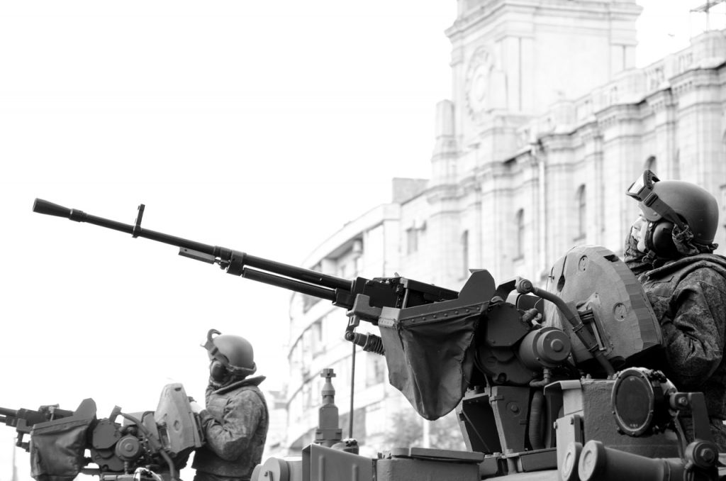 Black and white photo of soldiers riding on a military vehicle, showcasing their camaraderie and readiness.